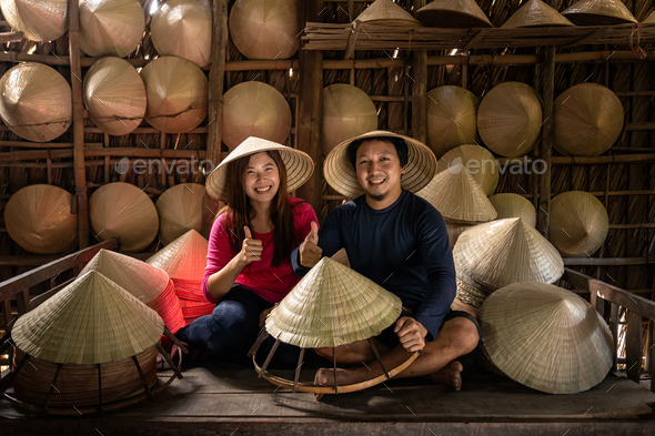 Asian couple traveler craftsman making the traditional vietnam hat in the old traditional house