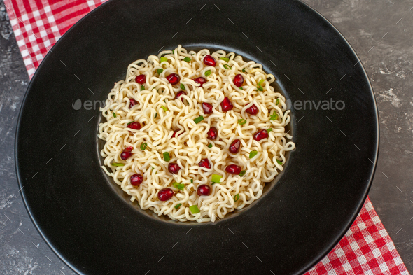 top close view ramen noodles on black round plate red and white checkered tablecloth on dark table