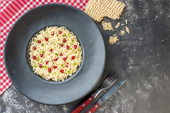 top view ramen noodles on dark round plate red and white checkered tablecloth fork and knife raw