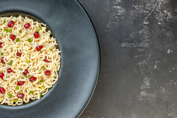 top half view ramen noodles on black round plate on dark table with free space