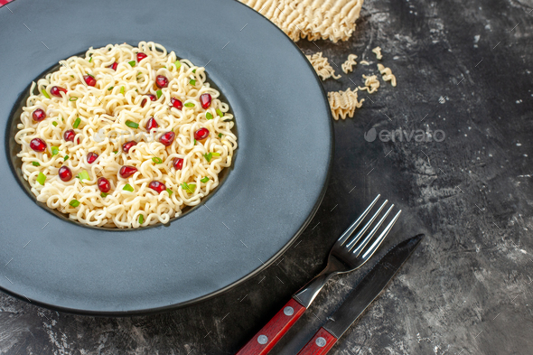 bottom view ramen noodles on dark round plate red and white checkered tablecloth fork and knife raw