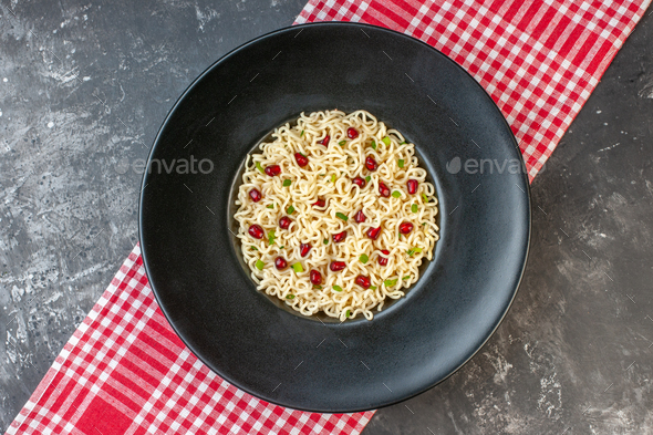 top view ramen noodles on black round plate red and white checkered tablecloth on dark table