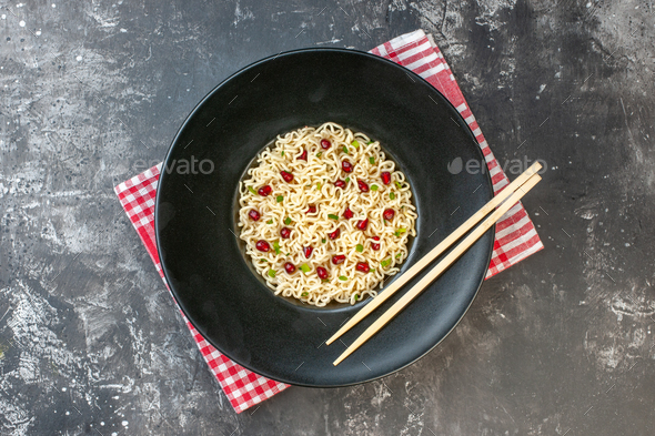 top view ramen noodles chopsticks on dark round plate red and white checkered tablecloth on dark