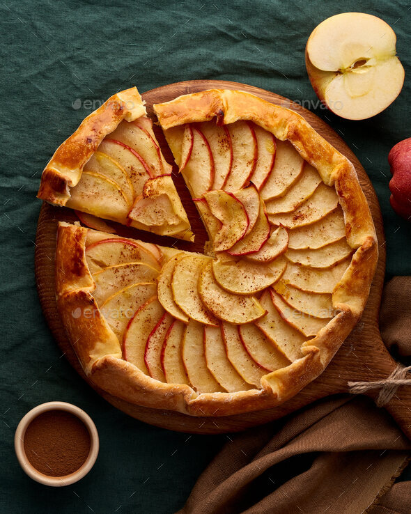 Apple pie, galette with fruits, sweet pastries on dark green tablecloth, vertical, top view
