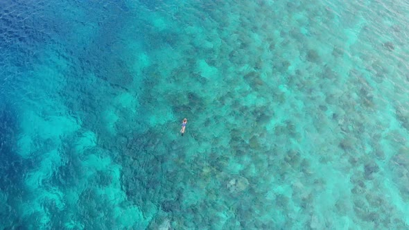 Aerial: woman snorkeling on coral reef tropical caribbean sea Indonesia Sulawesi alt