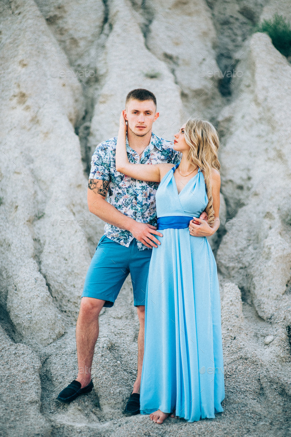 blonde girl in a light blue dress and a guy in a light shirt in a granite quarry