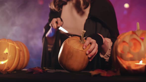 A witch carves a pumpkin for halloween. Beautiful lighting. Halloween! 4K.