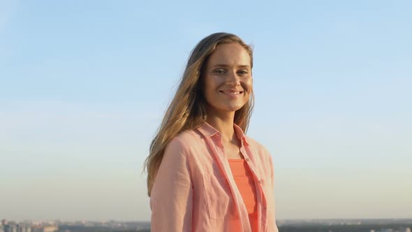 Pretty Blonde Girl Smiling and Touching Hair on Cityscape Background Slow-Mo