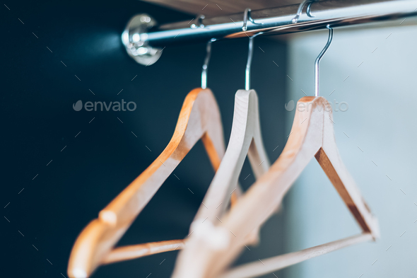 Colorful clothes hangers in empty wardrobe Stock Photo by
