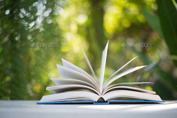 Close up of open book at home garden with nature bokeh background. Stock  Photo by Johnstocker