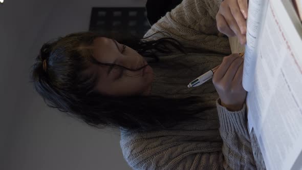 Female Teenage Student Doing Homework. Vertical Video, Low Angle, Locked Off alt