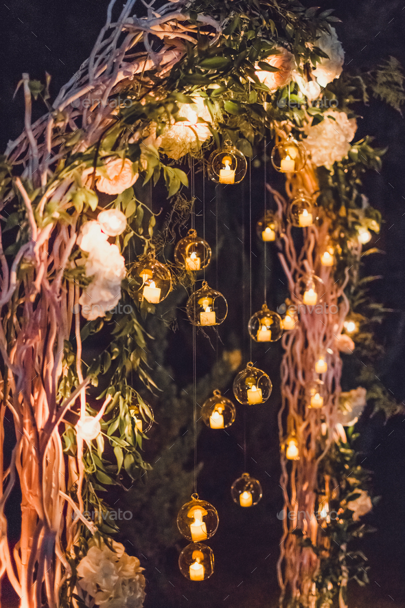 Night wedding ceremony, arch on party decorated with lights and candles ...