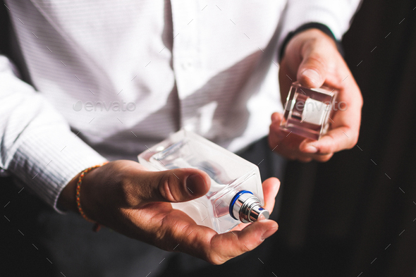 Man holding bottle of perfume and smells fragrance Stock Photo by  olegbreslavtsev