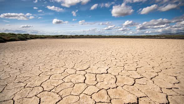 Panning over dry cracked sandy desert in Utah as clouds move through the sky alt