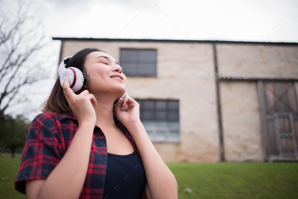 Young woman listening to music with mobile phone outdoor. Happy smiling girl listening to music. - Stock Photo - Images