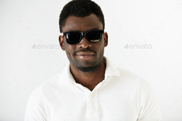 Portrait of fashionable African American man wearing white polo shirt and stylish sunglasses, lookin