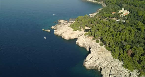 Rocky shore of Lokrum island. the camera passes over the dead sea within the trees on the island alt