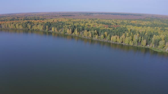 Aerial Footage of a Surface of the Lake Surrounded By Colorful Forest in Autumn