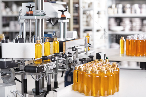 Bottles filled with soap yellow liquid standing on conveyor belt in factory. Automated process of cr