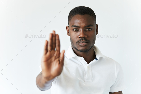 Headshot of dark-skinned young man wearing white polo shirt, preventing you from doing something wit
