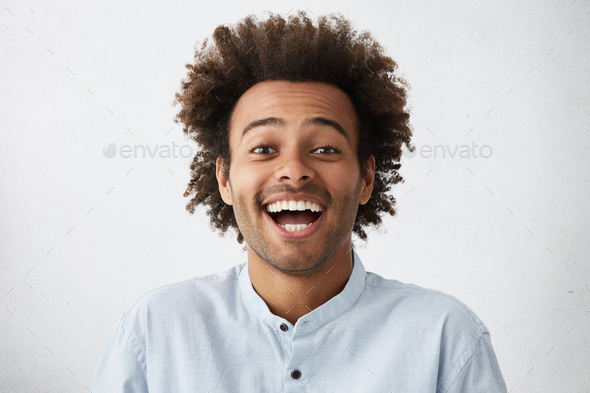Carefree joyful handsome Afro American man with bushy hairstyle and bristle having shining eyes open