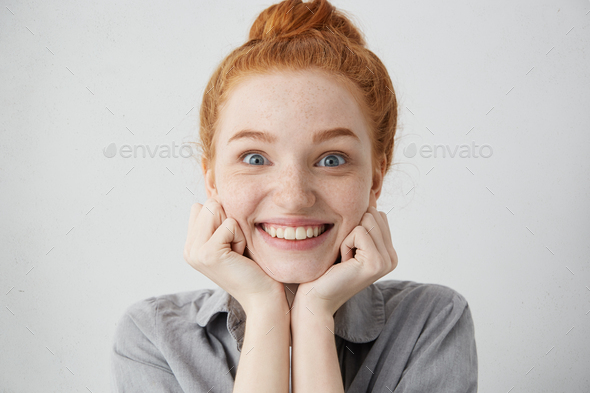 Tell me more. Close up shot of curious 20 y.o. redhead Caucasian woman pillowing face on her hands a