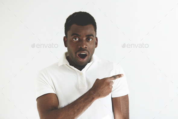 Portrait of shocked or astonished young black male with mouth wide open, in white polo shirt, showin