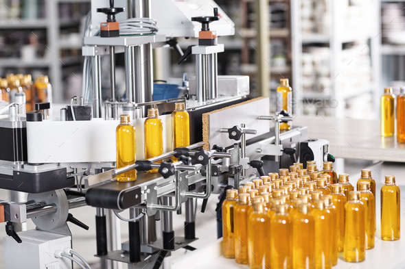 Cosmetics factory. Bottling line filled with yellow shampoo. Automated process on factory. Line of b