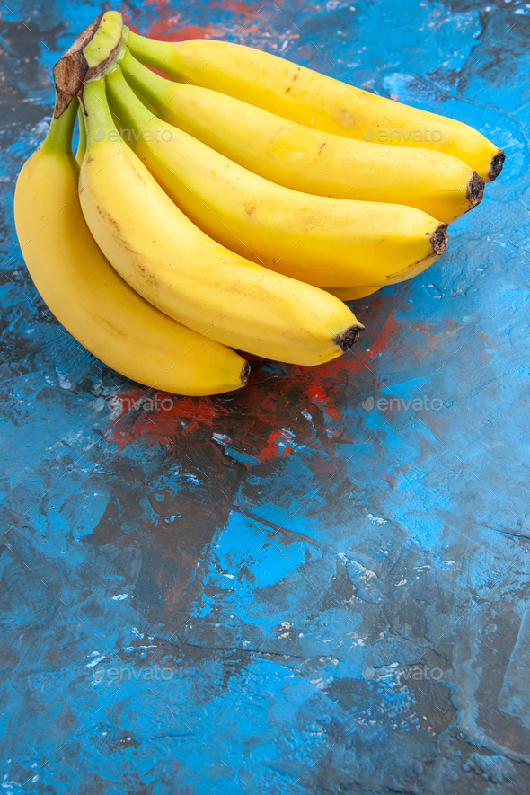 Vertical view of a bunch of fresh natural grown cavendish bananas on the  right side of isolated blue Stock Photo by ImgSolut