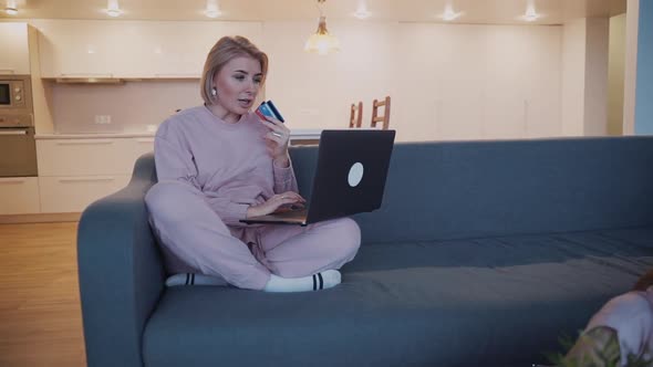 Woman Is Sitting at Sofa and Shopping Online Using High Tech Technology Laptop