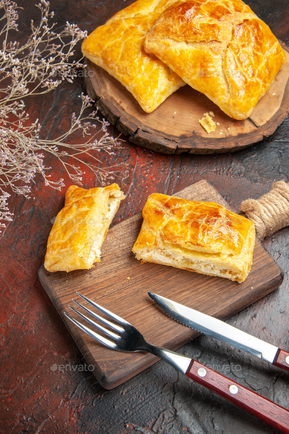 bottom view penovani khachapuri on wood board and on chopping board knife and fork on dark red table - Stock Photo - Images