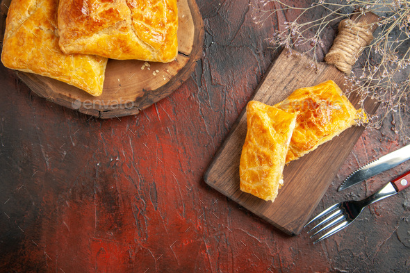top view penovani khachapuri on wood board and on chopping board knife and fork on dark red table - Stock Photo - Images