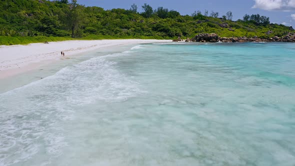 Aerial Low Altitude Fly Footage Over Tropical White Sand Beache with White Rolling Waves in alt