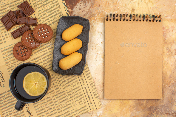 Different biscuits and tea in a black cup and notebook on mixed color  background Stock Photo by KamranAydinovStudio