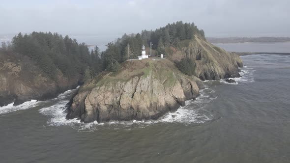 Cape Disappointment Lighthouse sits high above the churning pacific ocean waves, aerial orbit alt
