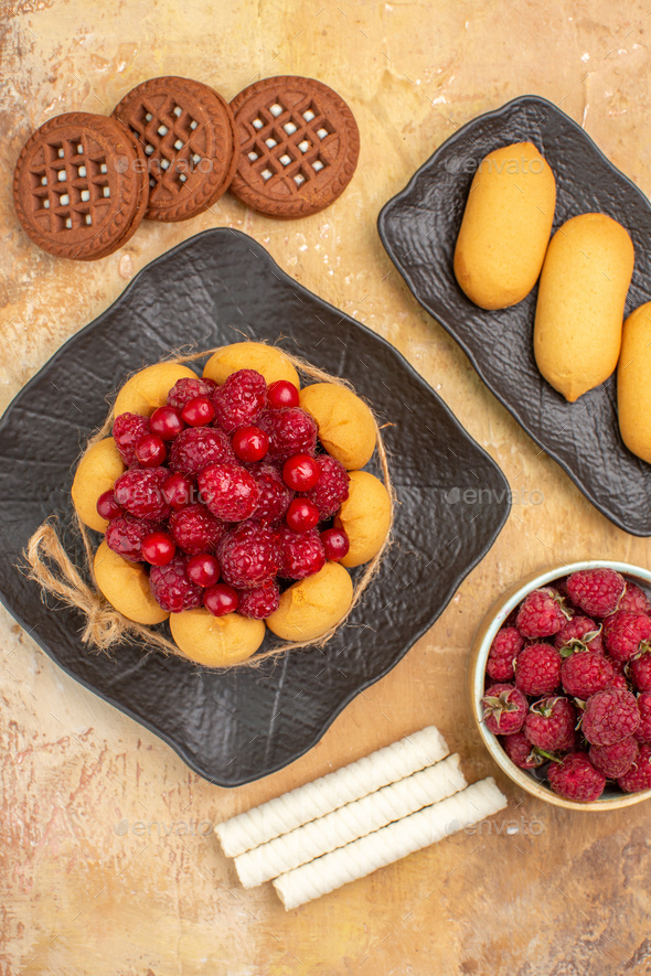 Vertical view of a gift cake and biscuits on brown plates fruits on mixed color background image
