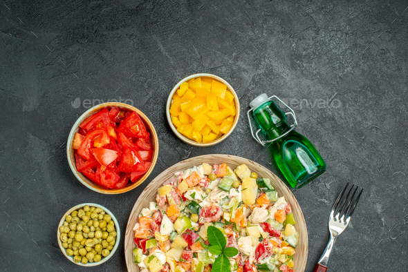 top close view of bowl of veggie salad with vegetables oil bottle and fork on side with free place