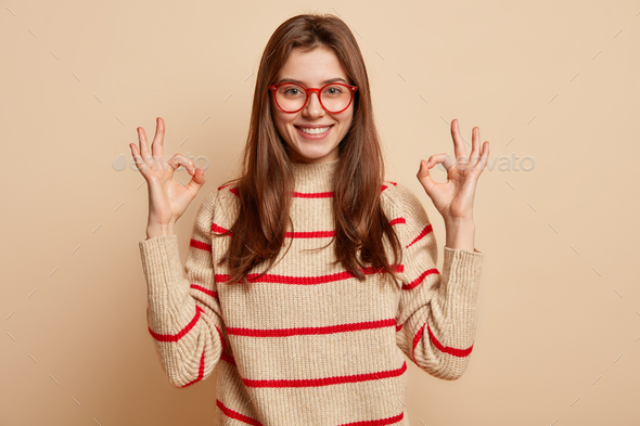Cheerful Caucasian lady shows zero gesture with both hands, being optimistic, expresses approval, sm