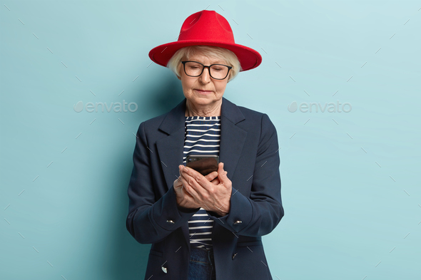 Fashionable senior woman texts on smartphone, satisfied with tariffs on internet, has online shoppin - Stock Photo - Images