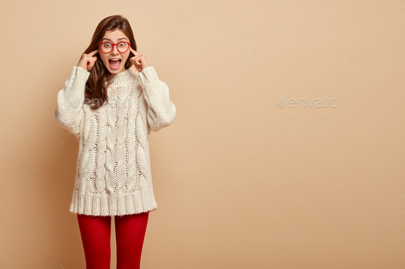 Emotional surprised female comes on loud party, dissatisfied with music, plugs ears, avoids noise, s