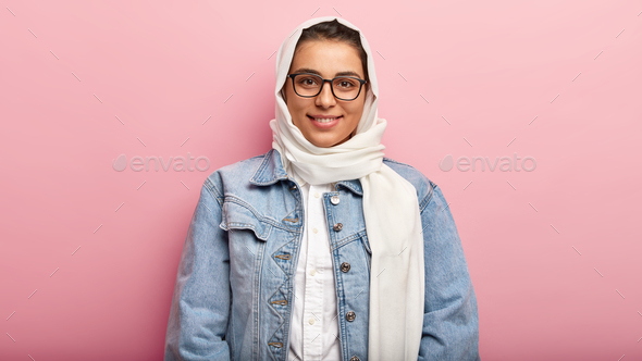 Headshot of good looking young Muslim woman with perfect smile, satisfied expression, being in good
