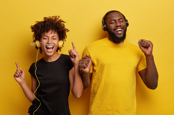 Overjoyed black woman and man gesture from happy emotions, have fun together, listen songs downloade
