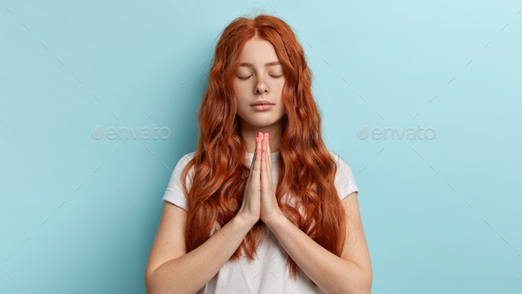 Gorgeous lovely ginger student keeps hands in praying gesture, believes in good luck at exam, has ca