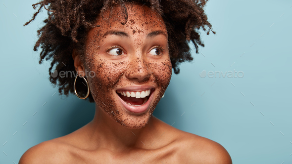 Topless happy woman applies natural coffee mask, looks aside with ...