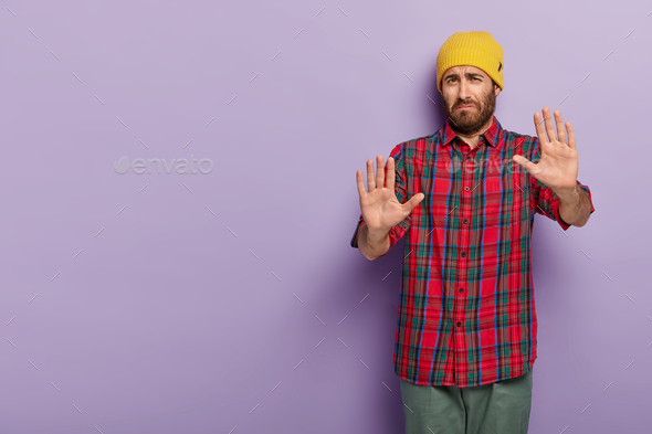 Dissatisfied sad man shows refusal sign, keeps palms outstretched at camera, says leave me in peace,