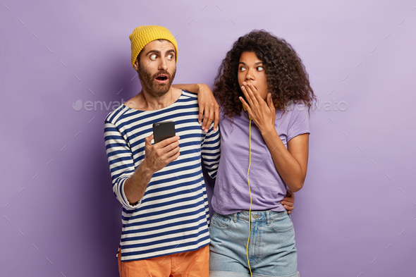 Amazed scared boyfriend and girlfriend feel surprised from received email on smartphone, get discoun