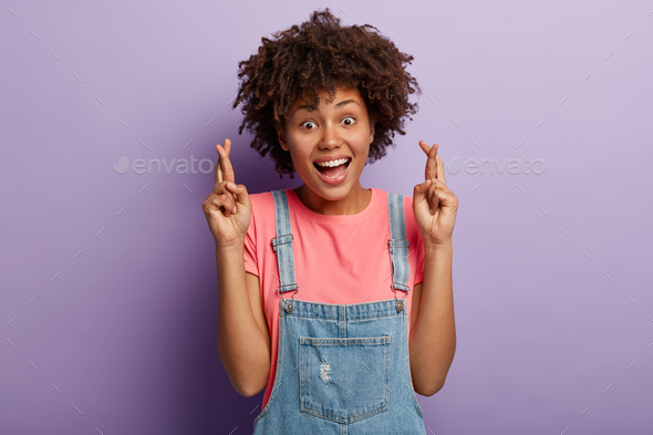 Glad smiling woman wishes luck, feels thrilled emotions, keeps fingers crossed, dreams about getting