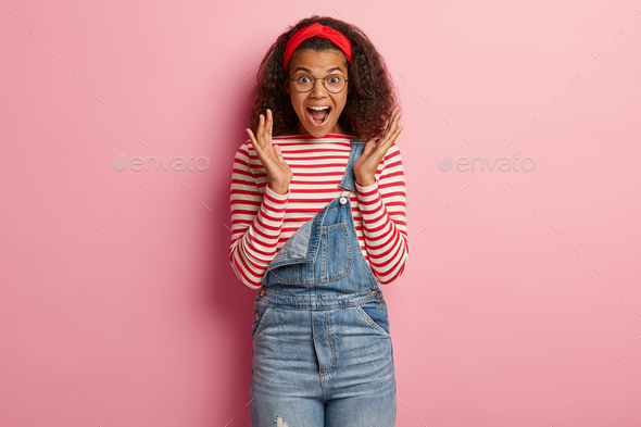 Excited happy curly Afro girl screams and gestures from positive emotions, wins expensive thing, exp