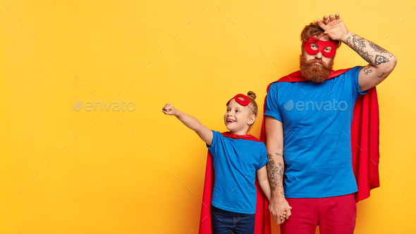 Fatigue super dad wipes sweat from forehead, wears mask and red cape, lovely little daughter keeps f