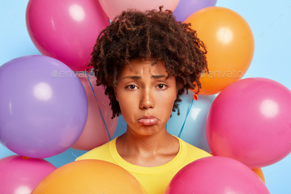 Headshot of sad desperate Afro woman purses lower lip, being in bad mood during party, has no friend